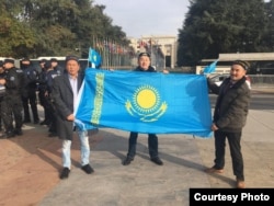 Женевадағы наразылық шарасындаҚыдырәлі Оразұлы, Өмірхан Алтын және Аманжан Сейіт (оңнан солға қарай) Қазақстан туын ұстап тұр. 6 қараша 2018 жыл.