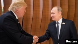 Президенты США и России Дональд Трамп и Владимир Путин пожимают друг другу руки во время саммита G20. Гамбург, 7 июля 2017 года