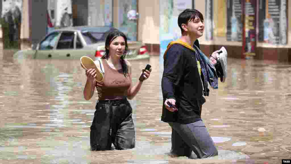 Вода поднялась выше колена. Смельчаки, рискнувшие перейти улицу, передвигаются босиком